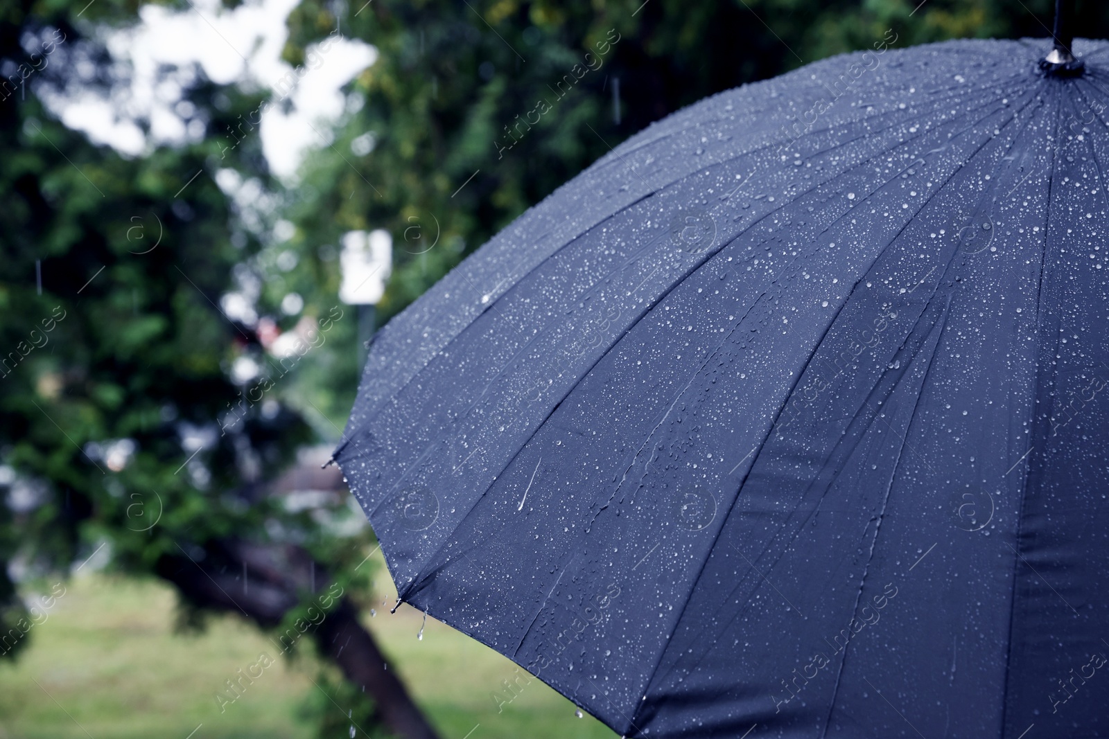 Photo of Blue umbrella under heavy rain outdoors, closeup. Space for text