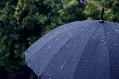 Photo of Blue umbrella under heavy rain outdoors, closeup