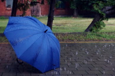 Photo of Blue umbrella on wet asphalt under heavy rain, space for text