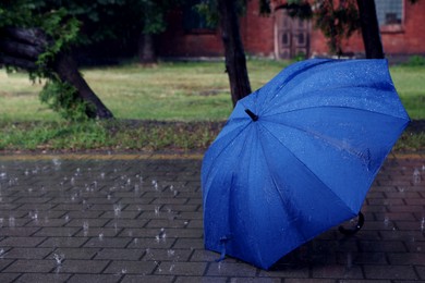 Photo of Blue umbrella on wet asphalt under heavy rain, space for text