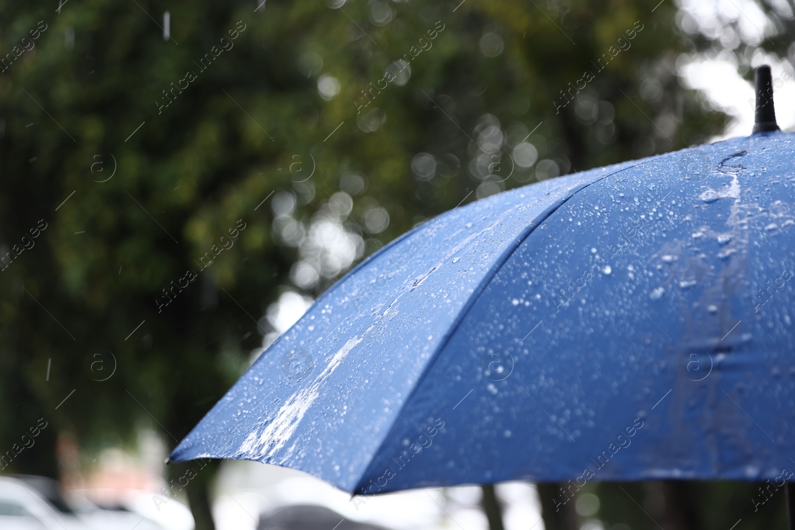 Photo of Blue umbrella under heavy rain outdoors, closeup. Space for text