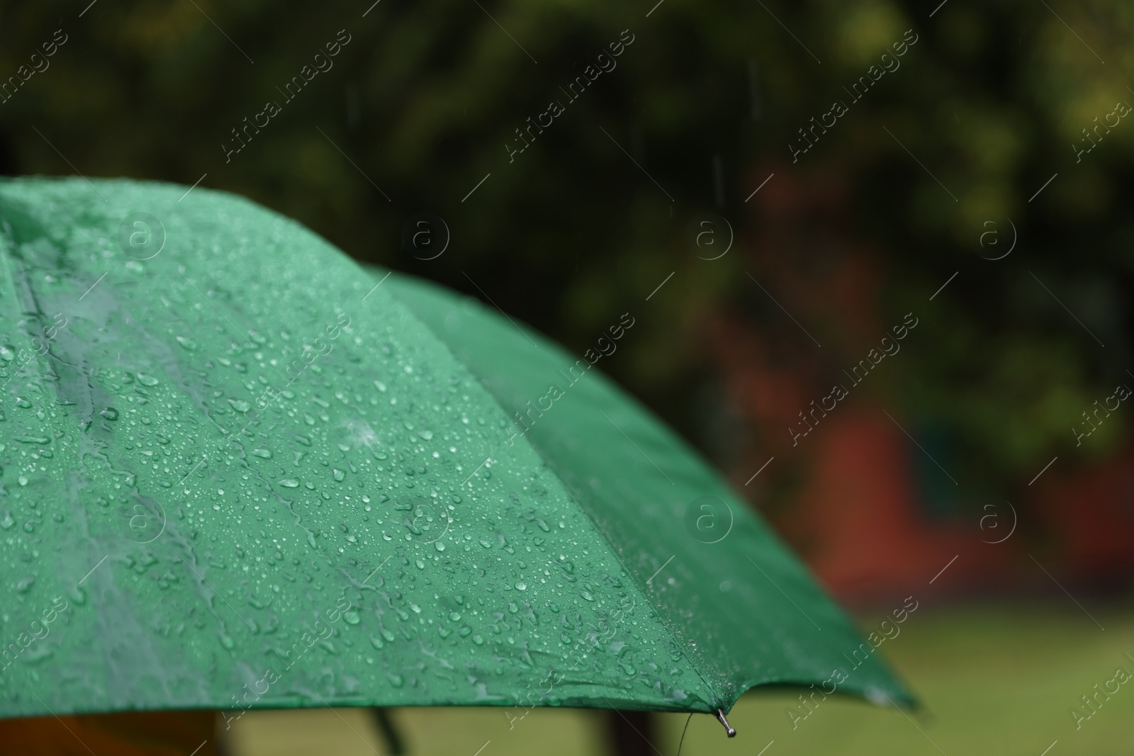 Photo of Green umbrella under heavy rain outdoors, closeup. Space for text