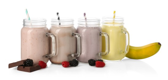 Photo of Different tasty milkshakes in mason jars and ingredients isolated on white