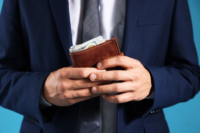 Photo of Man with dollars in wallet on blue background, closeup