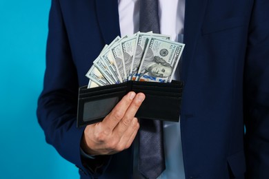 Photo of Man with dollars in wallet on blue background, closeup