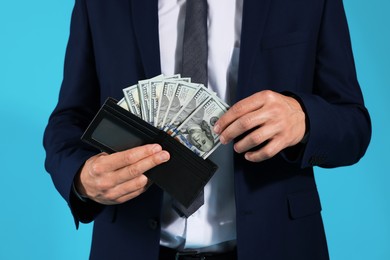 Photo of Man with dollars in wallet on blue background, closeup