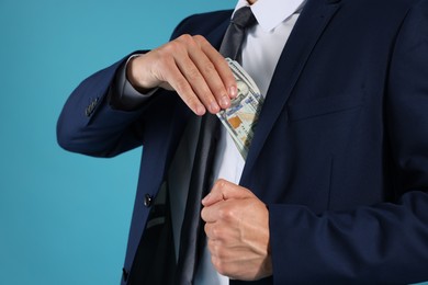 Photo of Man putting dollars in pocket on blue background, closeup