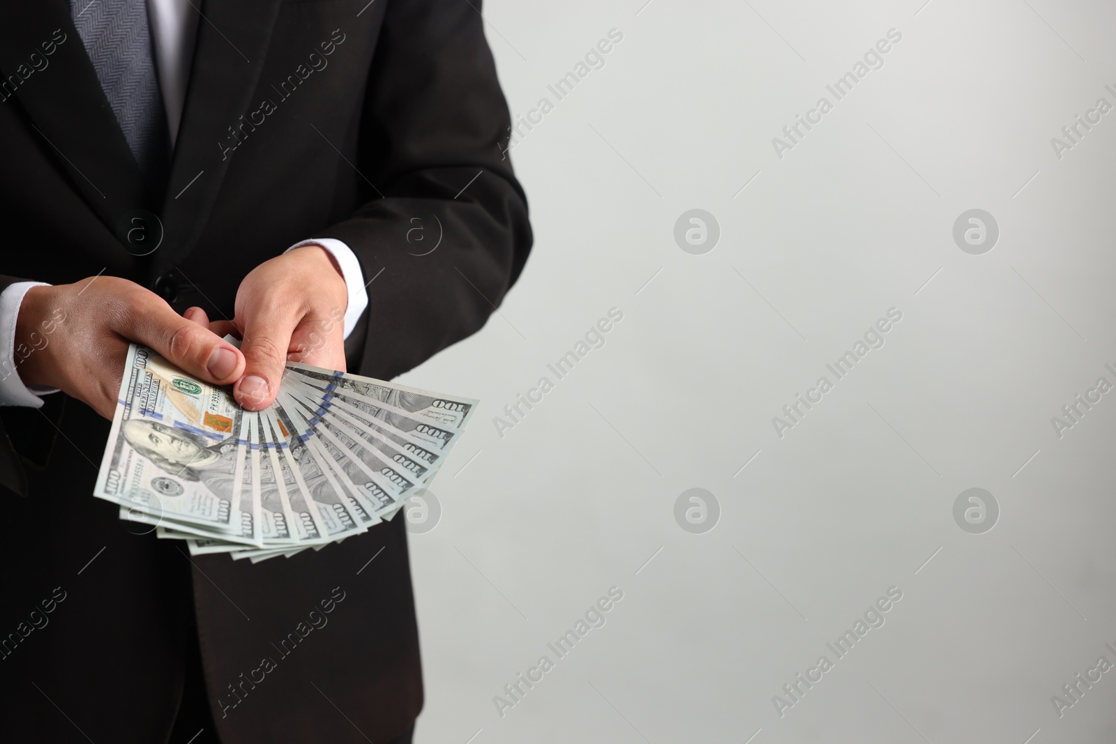 Man with dollar bills on light background, closeup. Space for text Photo of Man with dollar bills on light background, closeup. Space for text