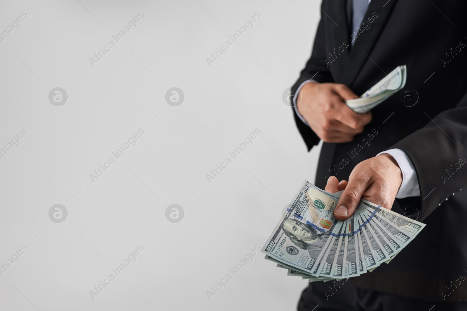 Man with dollar bills on light background, closeup. Space for text Photo of Man with dollar bills on light background, closeup. Space for text