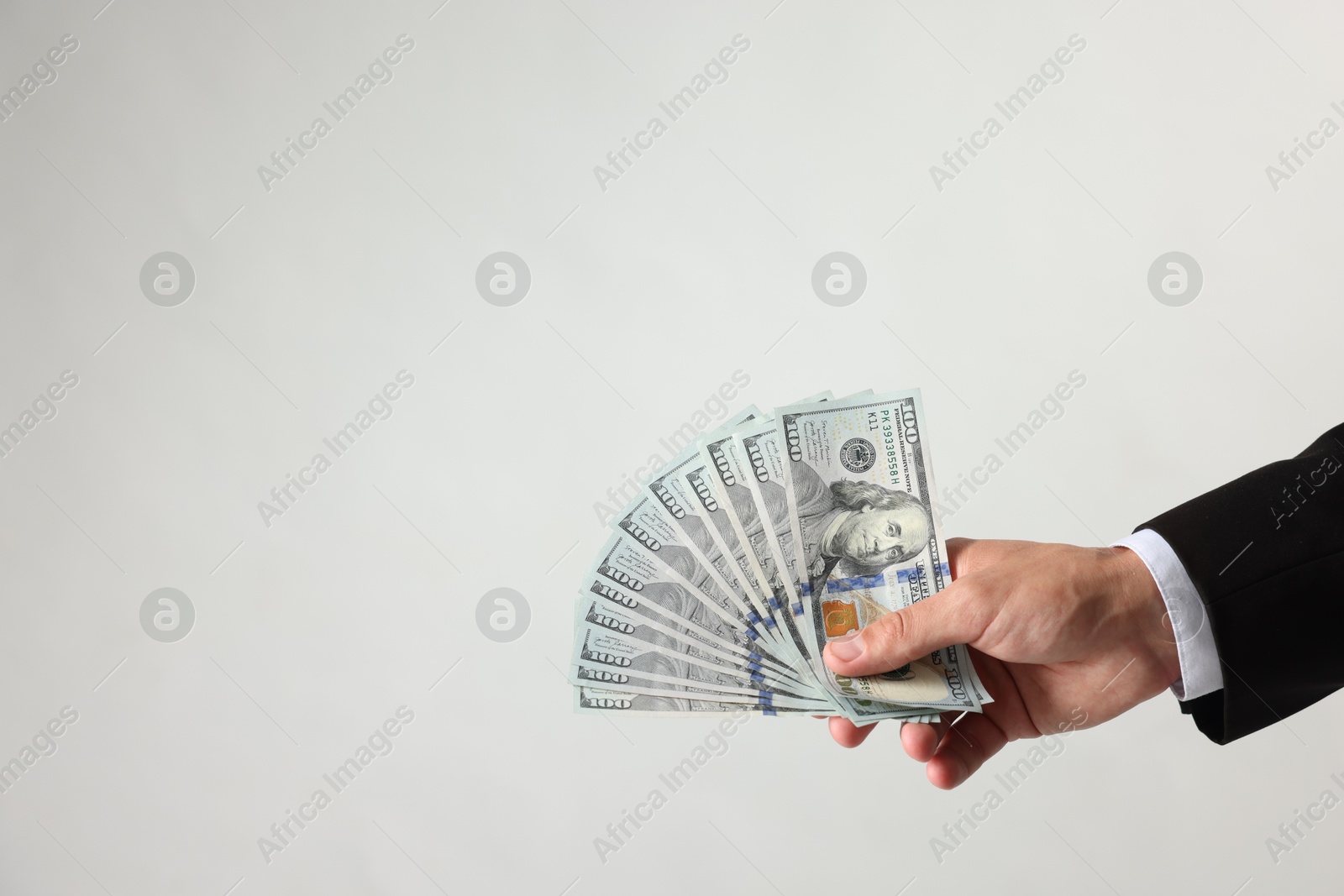 Man with dollar bills on light background, closeup. Space for text Photo of Man with dollar bills on light background, closeup. Space for text