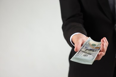 Photo of Man with dollar bills on light background, closeup. Space for text