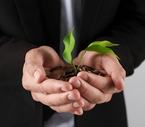 Photo of Man with coins and sprout on light background, closeup