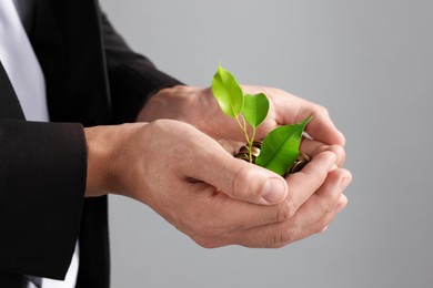 Photo of Man with coins and sprout on light background, closeup