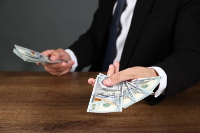 Photo of Man with dollar bills at wooden desk, closeup