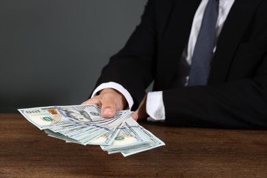 Photo of Man with dollar bills at wooden desk, closeup
