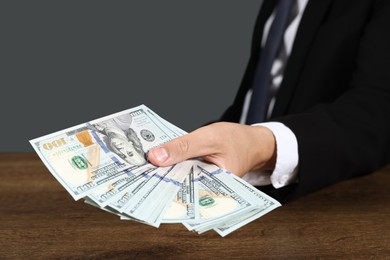 Photo of Man with dollar bills at wooden desk, closeup