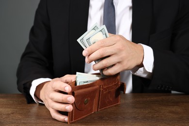 Photo of Man with dollars in wallet at wooden desk, closeup