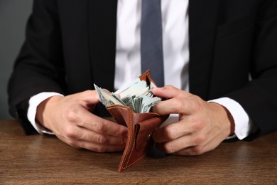 Photo of Man with dollars in wallet at wooden desk, closeup