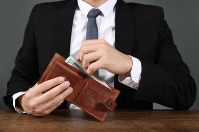 Photo of Man with dollars in wallet at wooden desk, closeup