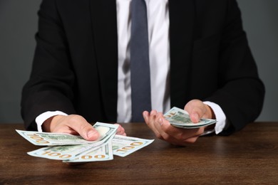 Photo of Man with dollar bills at wooden desk, closeup