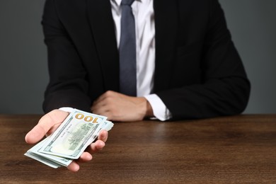 Photo of Man with dollar bills at wooden desk, closeup