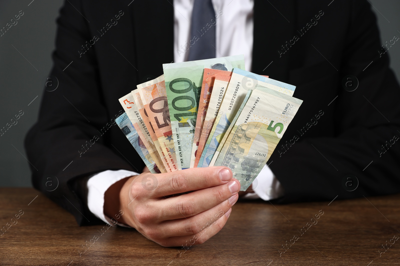 Man with euro banknotes at wooden desk, closeup Photo of Man with euro banknotes at wooden desk, closeup