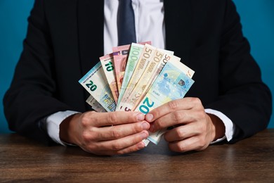 Photo of Man with euro banknotes at wooden desk, closeup