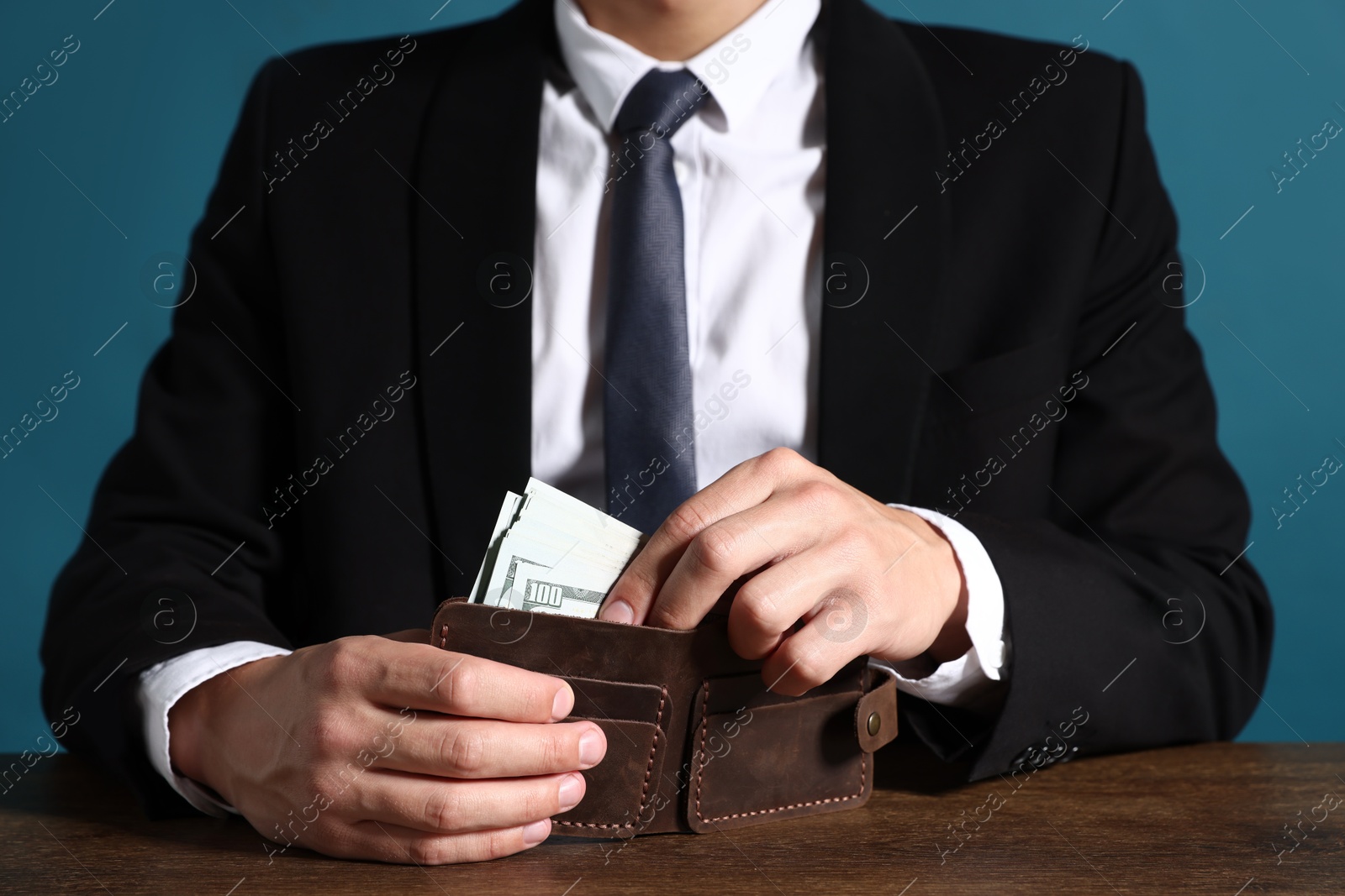 Man with dollars in wallet at wooden desk, closeup Photo of Man with dollars in wallet at wooden desk, closeup