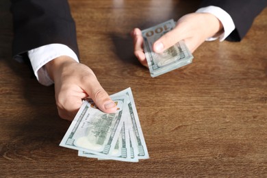 Photo of Man with dollar bills at wooden desk, closeup