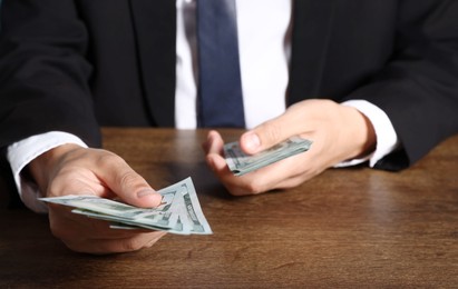 Photo of Man with dollar bills at wooden desk, closeup
