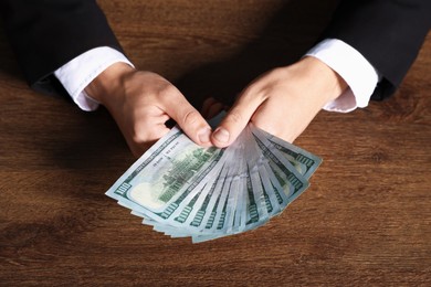Photo of Man with dollar bills at wooden desk, above view