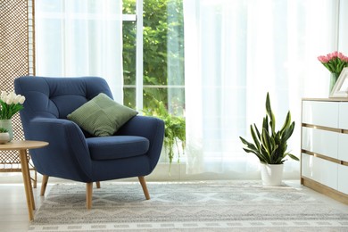 Photo of Stylish blue armchair near window with curtains indoors. Interior design