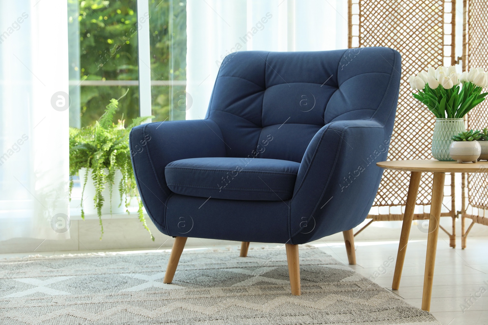 Photo of Stylish blue armchair near window with curtains indoors. Interior design