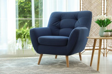 Photo of Stylish blue armchair near window with curtains indoors. Interior design
