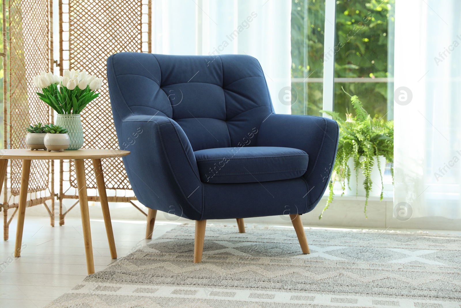 Stylish blue armchair near window with curtains indoors. Interior design Photo of Stylish blue armchair near window with curtains indoors. Interior design
