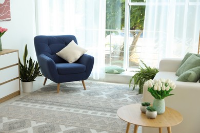Photo of Stylish blue armchair and houseplants near window with curtains indoors. Interior design