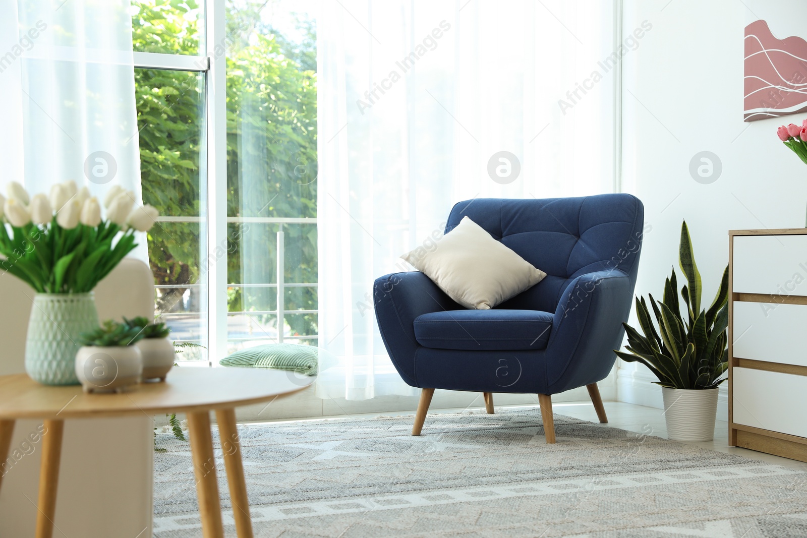 Photo of Stylish blue armchair near window with curtains indoors. Interior design