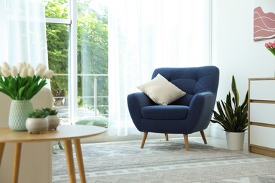 Photo of Stylish blue armchair near window with curtains indoors. Interior design