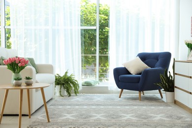 Photo of Stylish blue armchair and houseplants near window with curtains indoors. Interior design