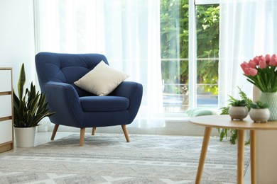 Photo of Stylish blue armchair and houseplants near window with curtains indoors. Interior design