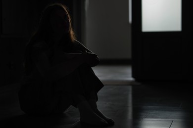 Photo of Silhouette of sad young woman at home, space for text