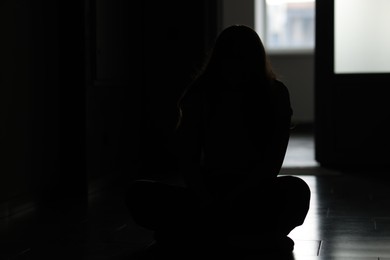 Photo of Silhouette of sad young woman at home