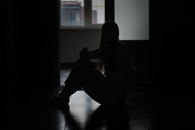 Photo of Silhouette of sad young woman at home