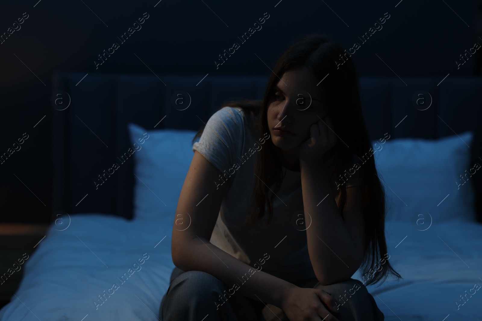 Sad young woman sitting on bed at home Photo of Sad young woman sitting on bed at home