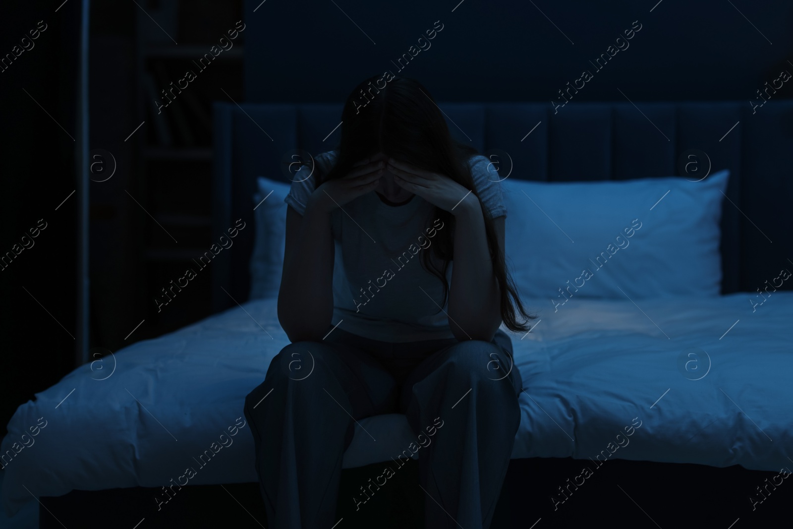 Sad young woman sitting on bed at home Photo of Sad young woman sitting on bed at home