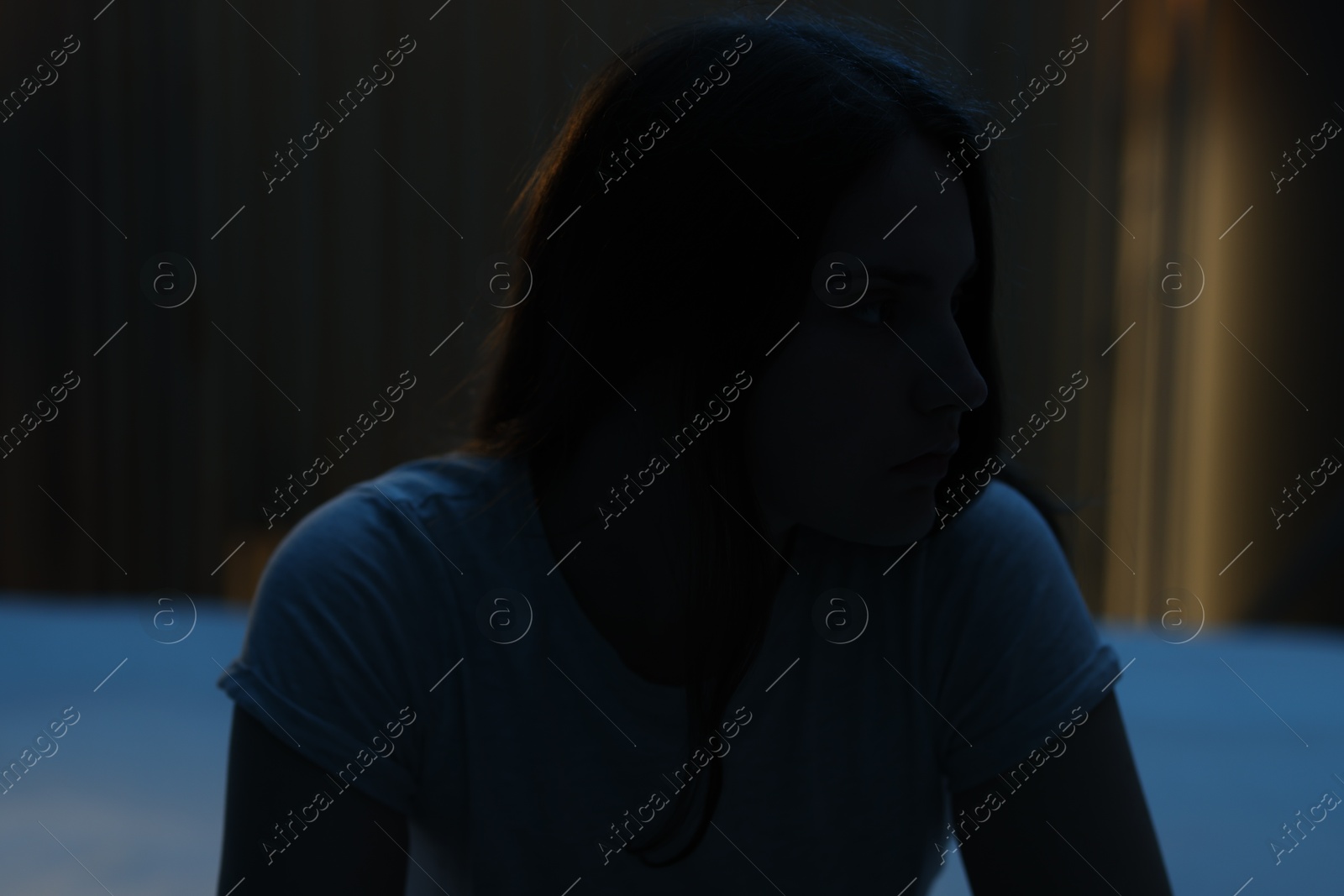 Sad young woman sitting on bed at home Photo of Sad young woman sitting on bed at home