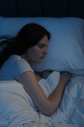 Photo of Sad young woman lying on bed at home