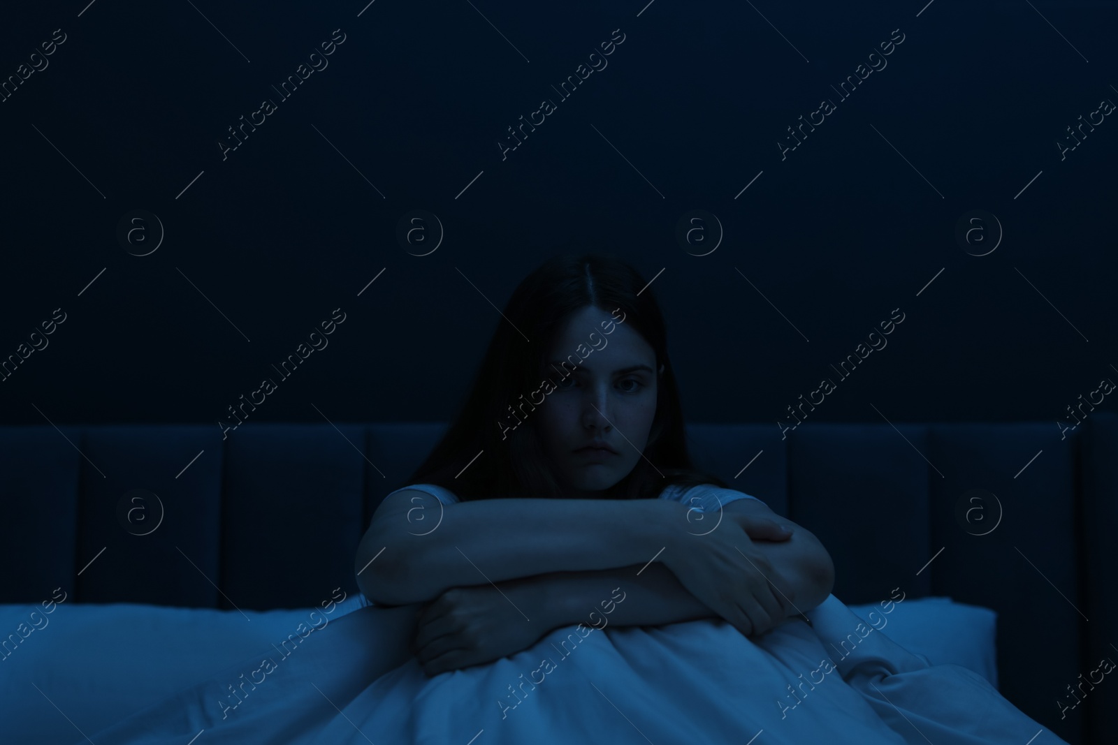 Sad young woman sitting on bed at home Photo of Sad young woman sitting on bed at home