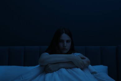 Photo of Sad young woman sitting on bed at home