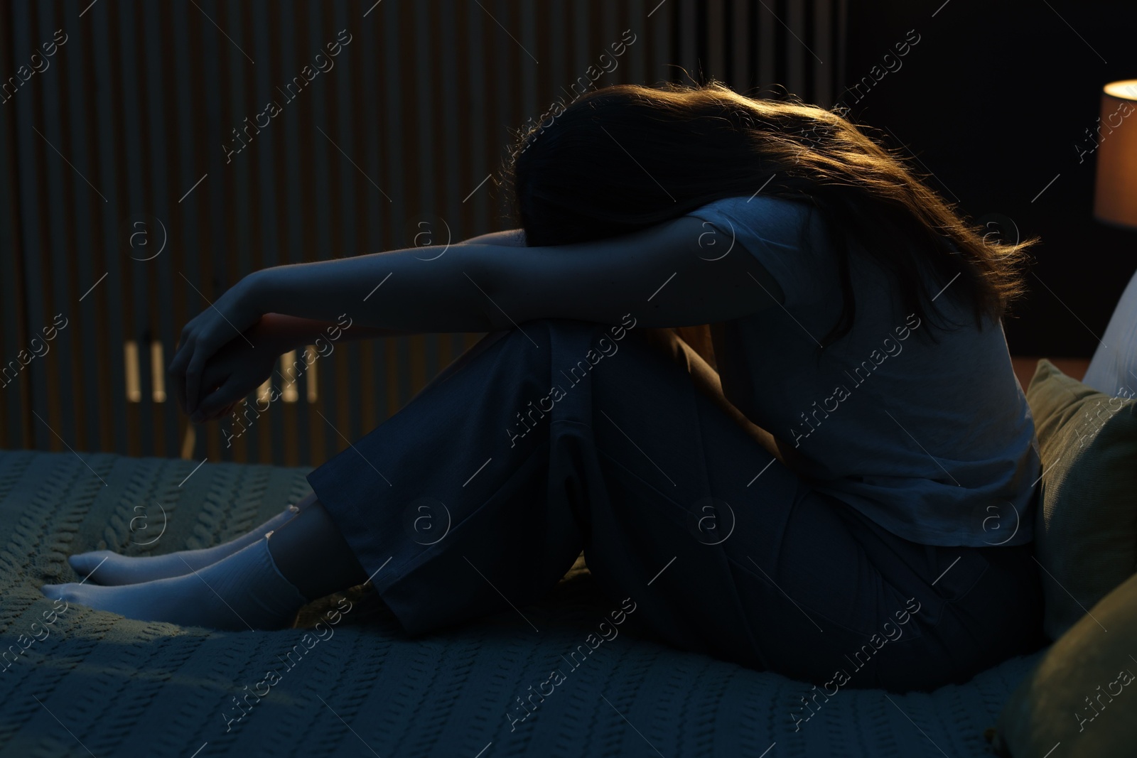 Sad young woman sitting on bed at home Photo of Sad young woman sitting on bed at home